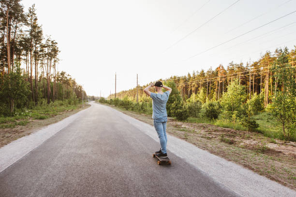 istock Rear view of young man riding with his longboard. 1155904925