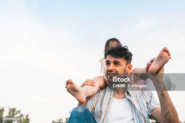 El Joven Papá Está Pasando Tiempo Con Su Pequeña Y Alegre Hija Al Aire Libre Imagen De La Niña Feliz Linda Jugando Con El Padre En El Parque Durante La Puesta De Sol Día De Los Padres Papá E Hija Comparten Amor Foto de stock y más banco de imágenes de Abrazar