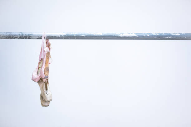 Cropped image of young ballerina sitting on bench, outdoors.