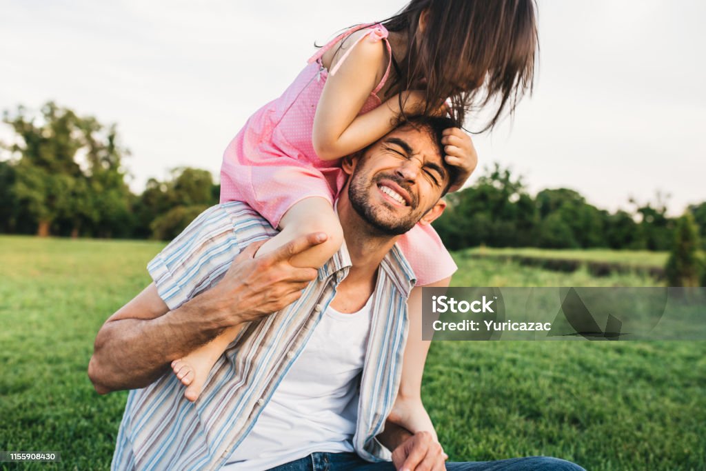 Outdoor image of funny dad spending good time together with his pretty daughter. Happy cute little girl playing with father in the park. Happy Father's Day. Daddy and daughter shares love. Fatherhood Adult Stock Photo