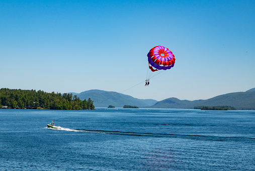 View of Lake George and mountains with two parasailing persons in the foreground.