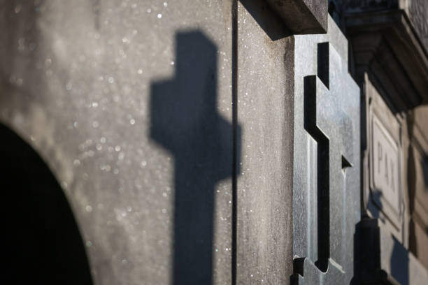 istock Tombstone with cross and shadow on the wall at cemetery 1155909776