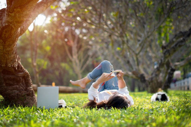 Holiday of me young woman enjoy listening music online on mobile phone , relax in summer time holiday laying on the grass field comfortable feeling nature park stock pictures, royalty-free photos & images