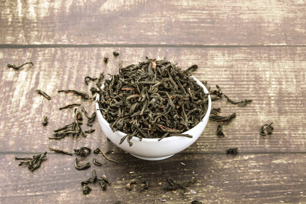 istock Dried tea is poured into a ceramic cup on a wooden plank table. 1155909949
