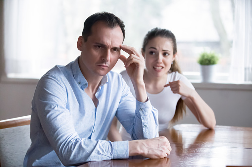 Couple in fight, man in focus. Depressed husband with headache ignoring screaming irritated woman. Big trouble, problem because of misunderstanding, conflict in family. Hard relationship concept