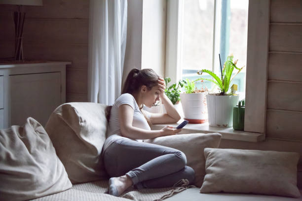 frau verärgert nach dem lesen schlechte nachricht am telefon zu hause - mobile phone telephone frustration women stock-fotos und bilder