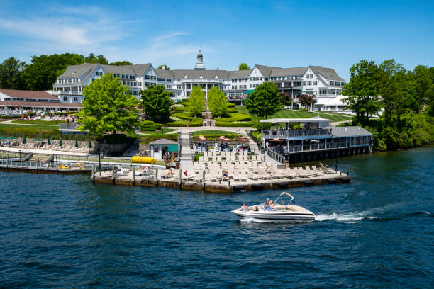 Sagamore - Lake George Wide view of the old section of the Sagamore Resort, taken from the deck of a closely passing ship with a power boat in the foreground. robertmichaud stock pictures, royalty-free photos & images