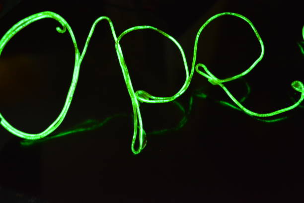 Lime green lighting with a specific pattern. Woven filaments, cable, wires with outgoing light. Neon electroluminescent wire with an inscription and letters open.