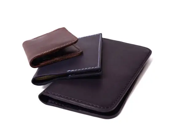 Handmade brown cardholder, black passport cover and purse isolated on white background closeup. Stock photo of isolated handmade luxury accessories.