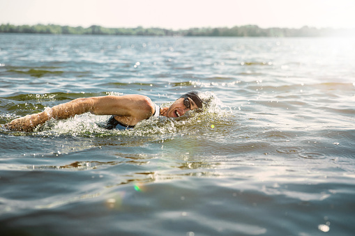 istock Professional triathlete swimming in river's open water 1155914840