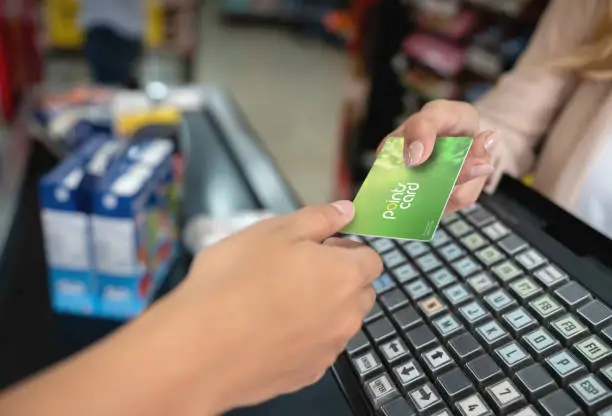 Close-up holding a rewards card at the supermarket - business concepts. **DESIGN ON CREDIT CARD WAS MADE FROM SCRATCH BY US**