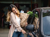 Woman multi-tasking getting in the car after shopping at the grocery store