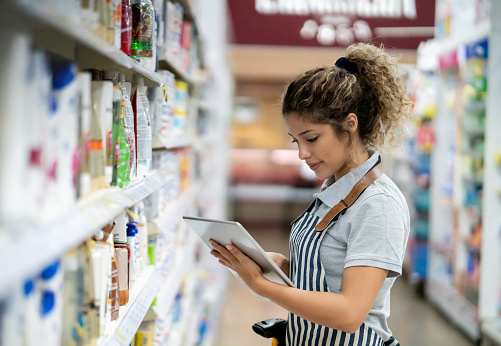 Portrait of a young woman doing inventory at the supermarket using a tablet computer â business concepts