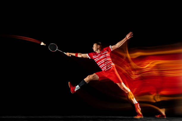 istock Young man playing badminton isolated on black studio background 1155921332
