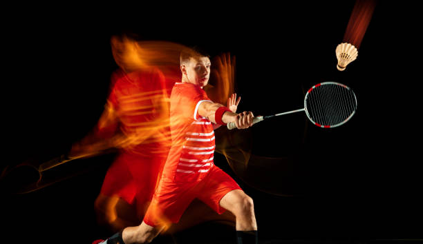 istock Young man playing badminton isolated on black studio background 1155921340