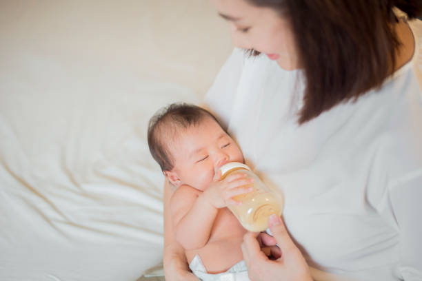 新生児の女の子は彼女の母親によってミルクを飲んでいます - male nurse 写真 ストックフォトと画像