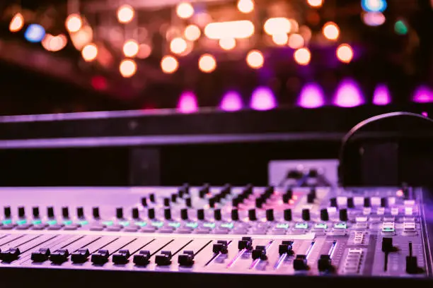Close up of a professional recording mixer desk, concert with lights in the blurry background