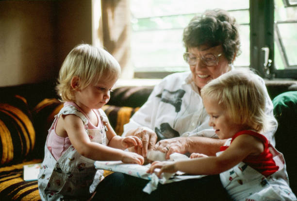 Toddlers opening gift with grandmother