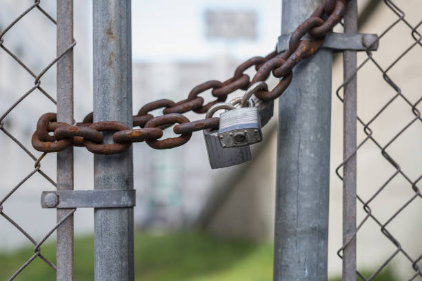 istock Rusty chain with padlock on a closed fence 1155928119