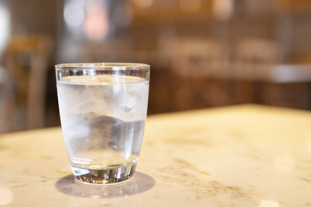 istock Glass of water with ice cubes on marbled table at restaurant with copy space. 1155931585