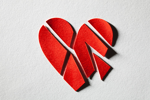 Broken heart. Red cut paper heart on a white background.