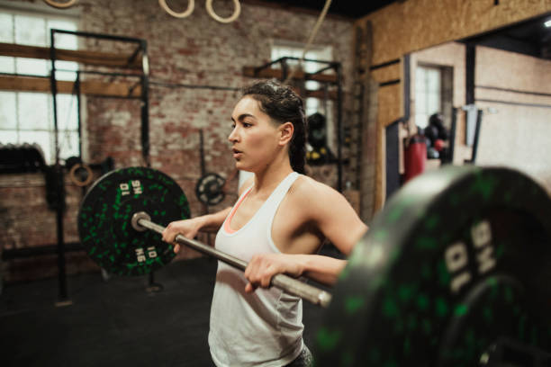 Woman Weightlifting Female cross training ter preforming a clean and jerk while at a cross training  gym. clean and jerk stock pictures, royalty-free photos & images