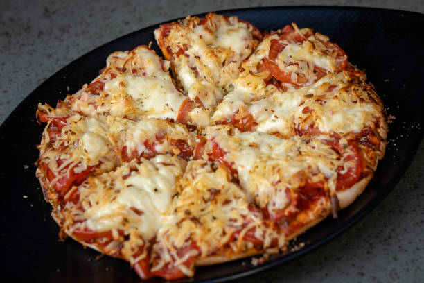 istock Homemade pizza on a black plate, close up 1155936770
