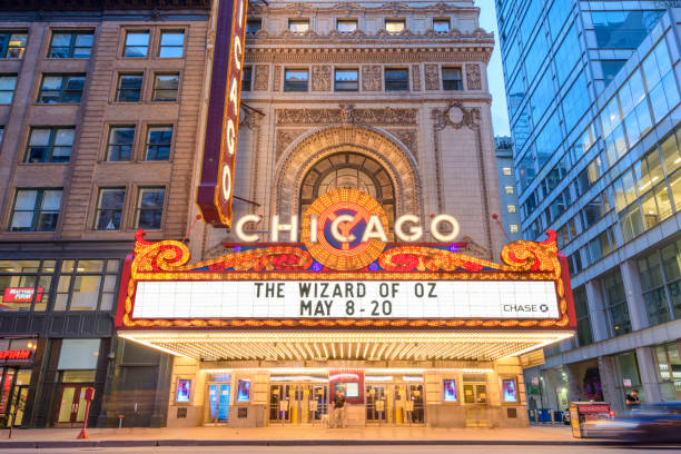 Chicago Theatre Chicago, Illinois, USA - May 10, 2018: Pedestrians and visitors pass below the Chicago Theatre on State Street at twilight. The historic theater dates from 1921. theatre building stock pictures, royalty-free photos & images