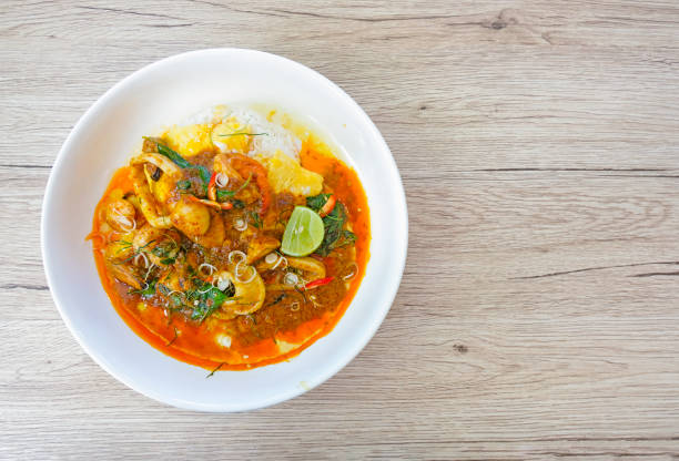 istock Stir fried chilli shrimp squid sea shells wrapped in thick eggs in a white dish on a wooden background from top view. 1155938012