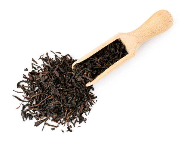 乾燥した紅茶の葉は、白い上に木製のスプーンからこぼれた。上部のフォーム。 - 紅茶 ストックフォトと画像