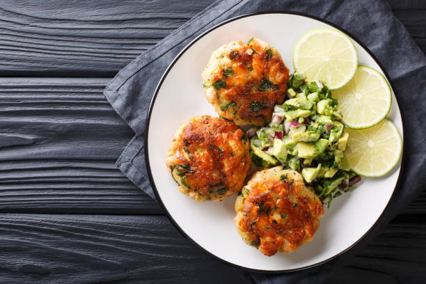 köstliche gesunde lachsfritten mit avocado-salsa und limette-nahaufnahme auf einem teller. horizontale obere ansicht - fish cutlet stock-fotos und bilder