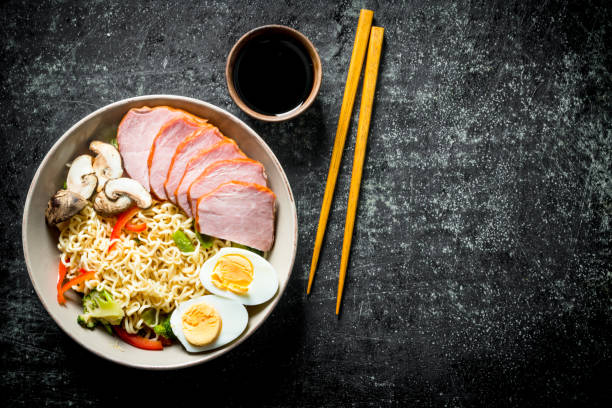 istock Instant noodles with vegetables, egg, ham, soy sauce and chopsticks. 1155944862