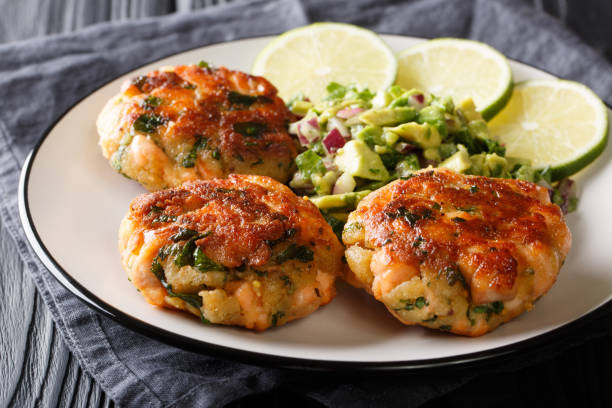 istock Recipe fried salmon patties with fresh avocado salsa and lime closeup on a plate. horizontal 1155945914