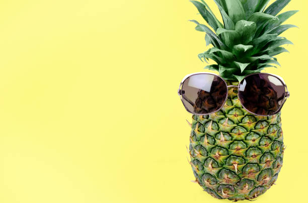 istock Pineapple with sunglasses on yellow background 1155945984