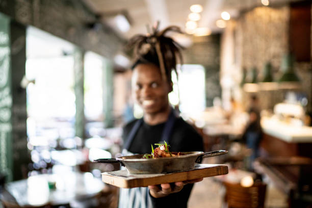 istock Smiling male chef holding prepared dish at restaurant 1155946327