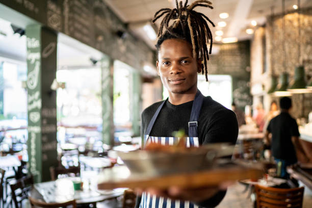 istock Serious male chef holding prepared dish at restaurant 1155947024