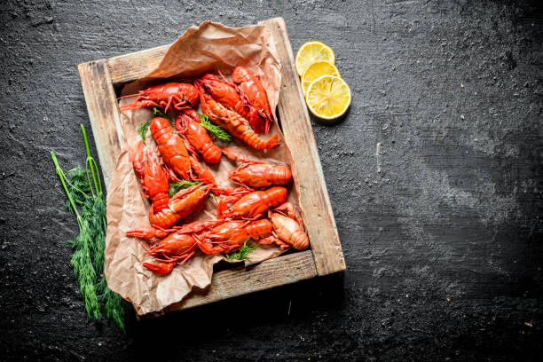 istock Boiled crayfish on paper in tray with dill and lemon. 1155949924