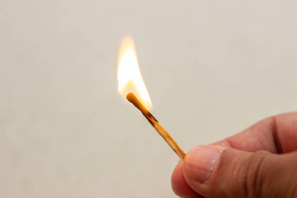 istock Lit match in hand. A lit match on a white background. Lighted match in hand on white background. Burning match in hand. Burning match on white background 1155952326