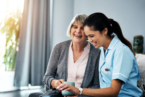 Nothing lifts the spirit like laughter Shot of a young nurse chatting with a senior woman at home resting stock pictures, royalty-free photos & images