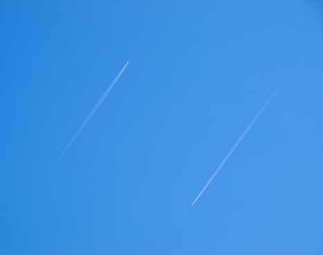 Two passenger aircraft flying nearby. Condensation trail from an airplane in a blue sky.
