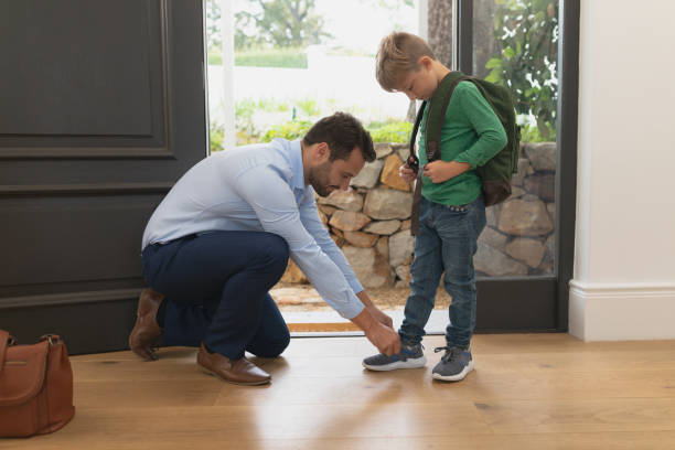 istock Father tying his sons shoelaces in a comfortable home 1155953802