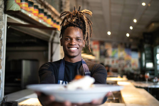 istock Smiling male chef holding prepared dish at restaurant 1155954578