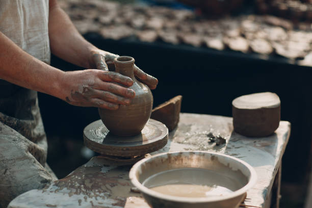 istock Potter makes clay pot jar on potter's wheel 1155954702