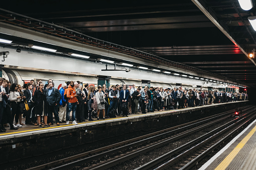 London, UK - June 6, 2019: Large group of people on a platform of Moorgate station of London Undeground, trains delayed. London Underground is the oldest underground railway in the world.