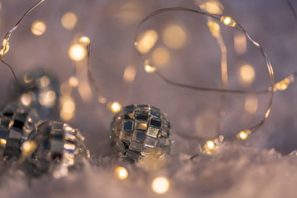 istock Small decorative balls with a mirror and a luminous garland on a snow. Blurred festive gray background with yellow bokeh. 1155958151