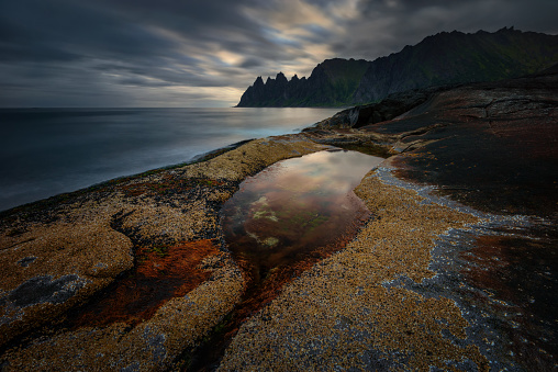 Tugeneset rocky coast with mountains in background at sunset, Norway