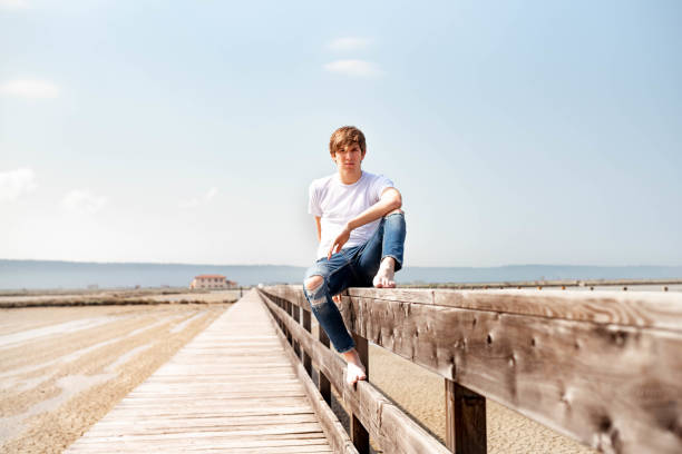 istock Young man sitting on a wooden fence 1155961878