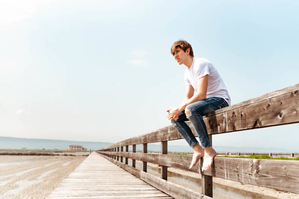 istock Young man sitting on a wooden fence 1155961884