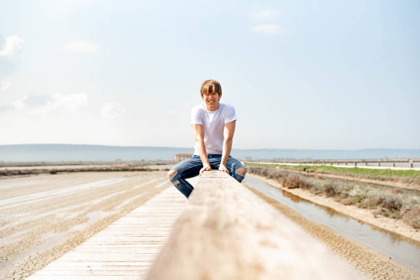 istock Young man sitting on a wooden fence 1155961898