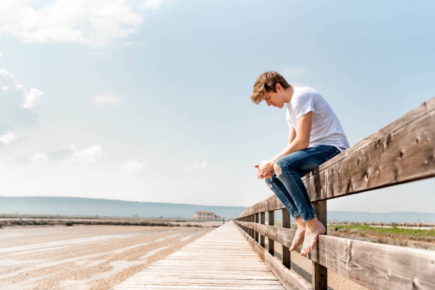 istock Young man sitting on a wooden fence 1155961900